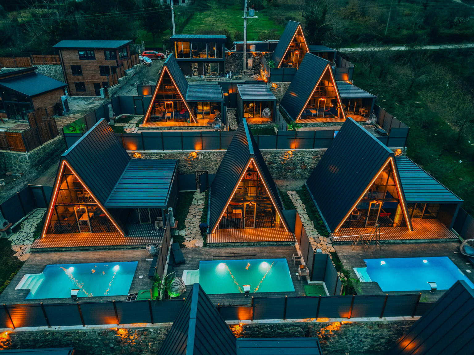 Üçgen çatılı bungalov evler havadan — havuzlu, gece aydınlatması